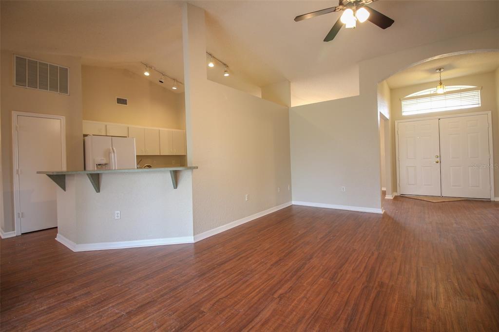 An open-concept living area features wood-look flooring, a kitchen breakfast bar, and vaulted ceilings — 3002 CHASEWOOD DRIVE, LAKELAND, FL