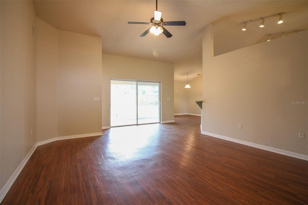 A living room with wood-look flooring, a ceiling fan, and a sliding glass door — 3002 CHASEWOOD DRIVE, LAKELAND, FL