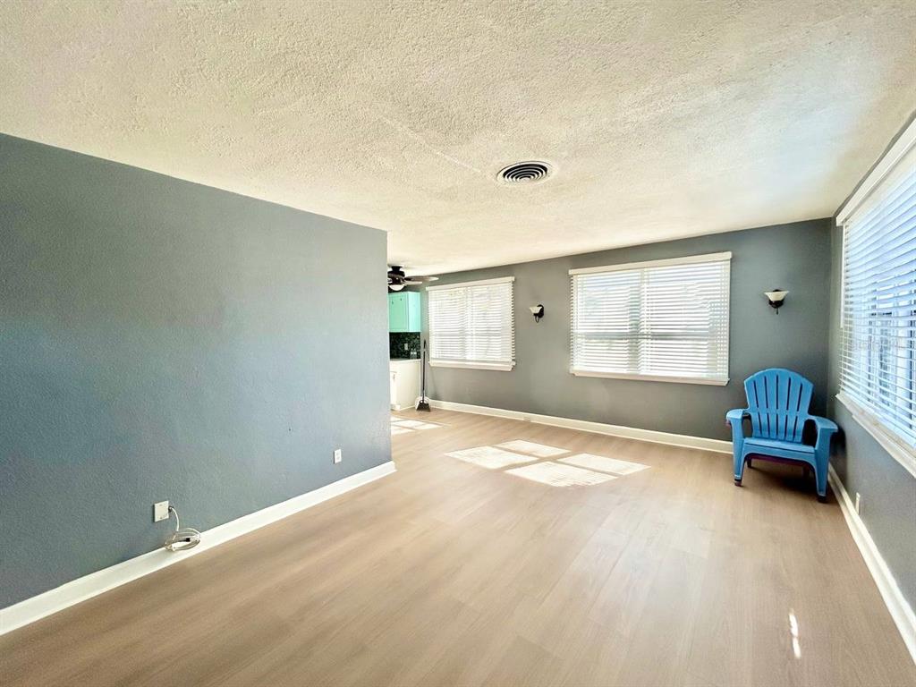 An empty living room features gray walls, light wood-look flooring, and a bright blue chair — 2720 EDWARDS AVENUE S, ST PETERSBURG, FL