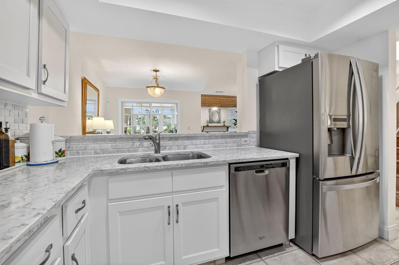 A kitchen with white cabinets, marble-look countertops, a stainless steel dishwasher, and a refrigerator — 6062 Glendale Drive, Boca Raton FL 33433, BOCA RATON, FL