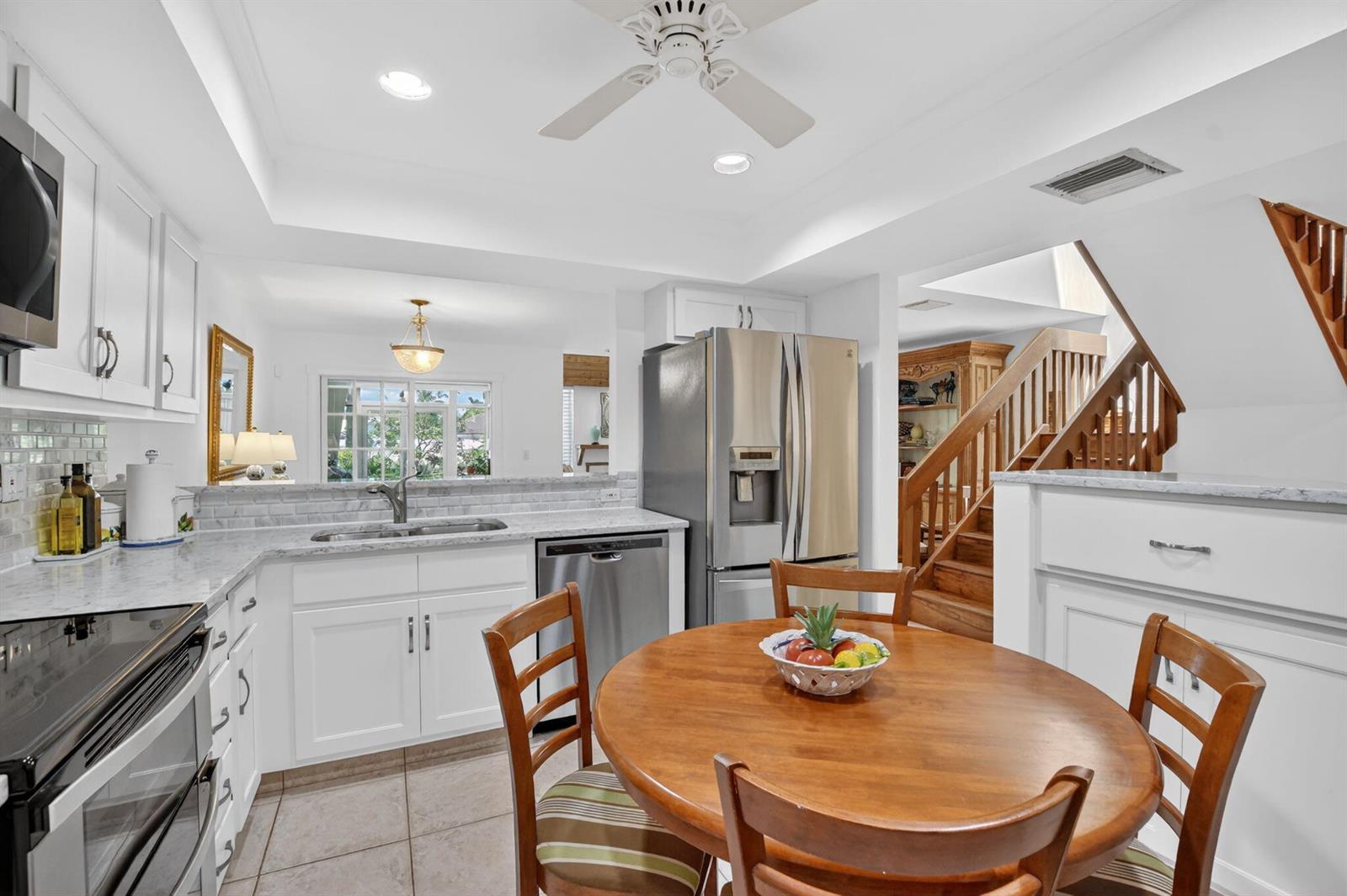 A kitchen with white cabinets, stainless steel appliances, and a round wooden dining table — 6062 Glendale Drive, Boca Raton FL 33433, BOCA RATON, FL