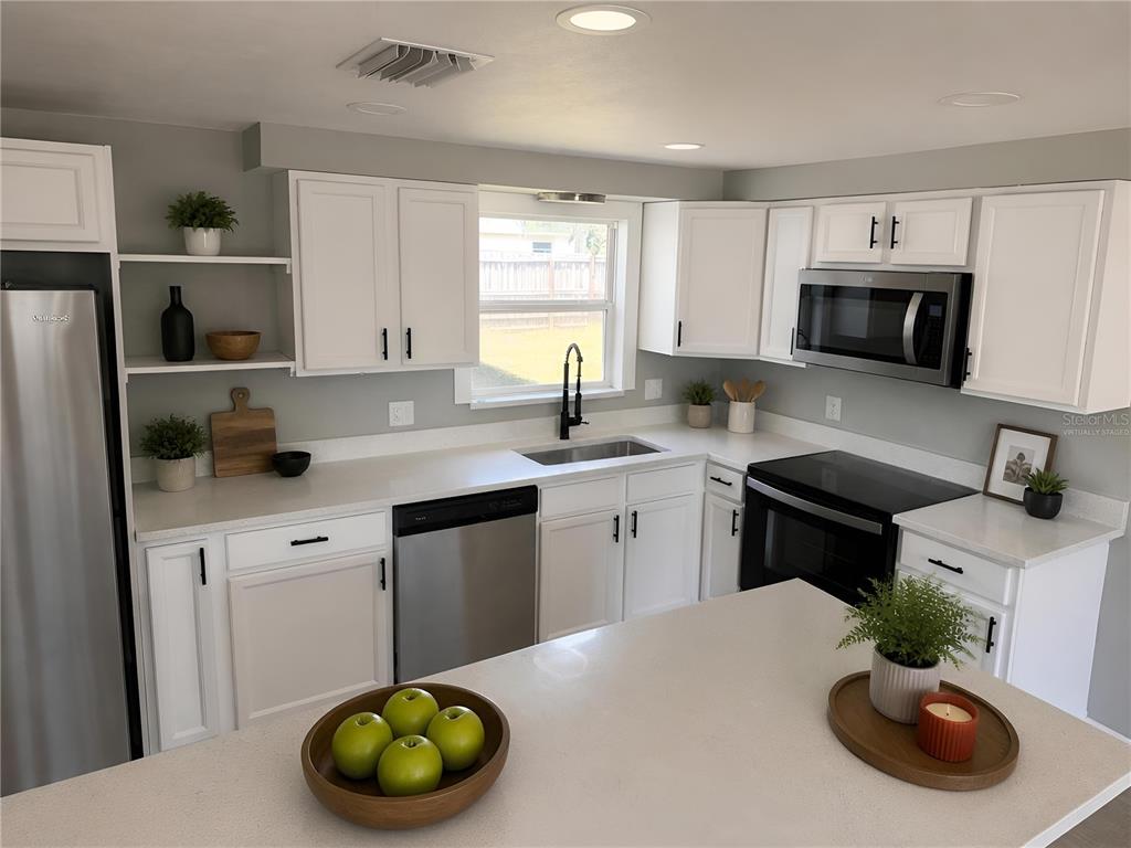 A kitchen with white cabinets, stainless steel appliances, and a central island with a bowl — 3511 CAMBRIDGE STREET, NEW PORT RICHEY, FL