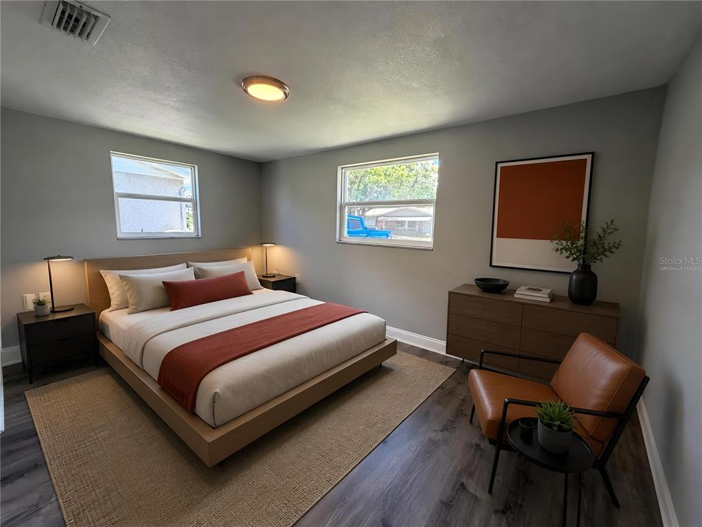 A bedroom with gray walls, wood flooring, a platform bed, and a leather accent chair — 3511 CAMBRIDGE STREET, NEW PORT RICHEY, FL
