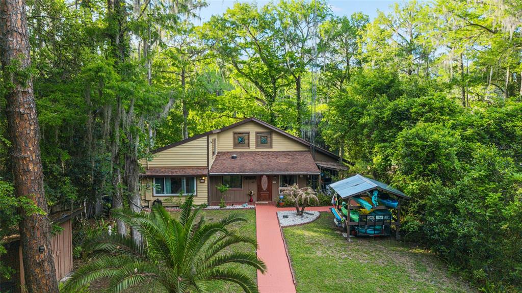 An aerial view shows a two-story house with tan siding surrounded by dense green trees — 11144 SW 190TH AVENUE, DUNNELLON, FL
