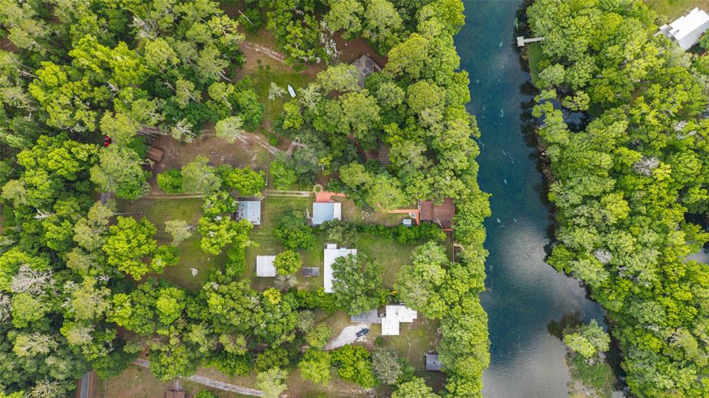 An aerial view shows several houses nestled among dense trees along a narrow river — 11144 SW 190TH AVENUE, DUNNELLON, FL