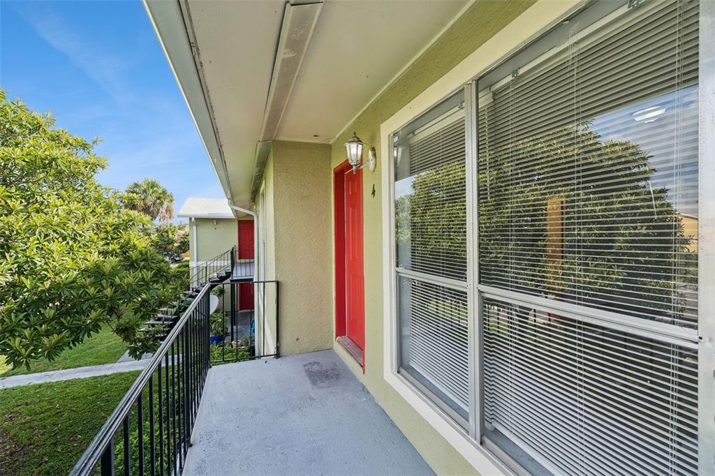 An exterior view of an apartment balcony with a red door and metal railings — 1847 CARALEE BOULEVARD UNIT 4, ORLANDO, FL