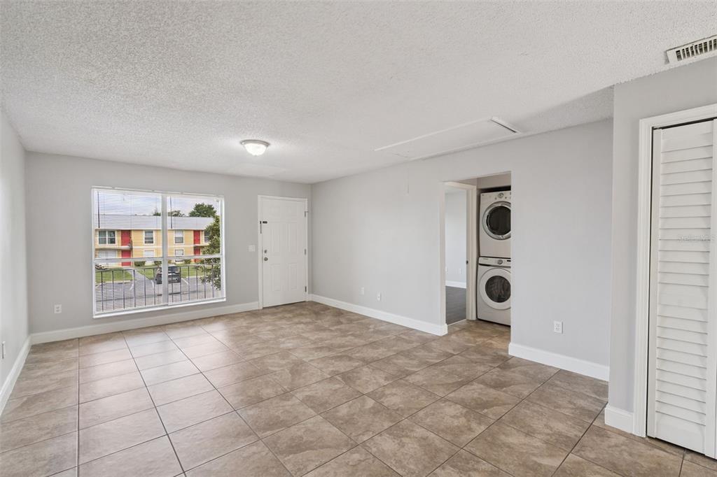 A living room with light gray walls, tile flooring, a window, and a laundry closet — 1847 CARALEE BOULEVARD UNIT 4, ORLANDO, FL