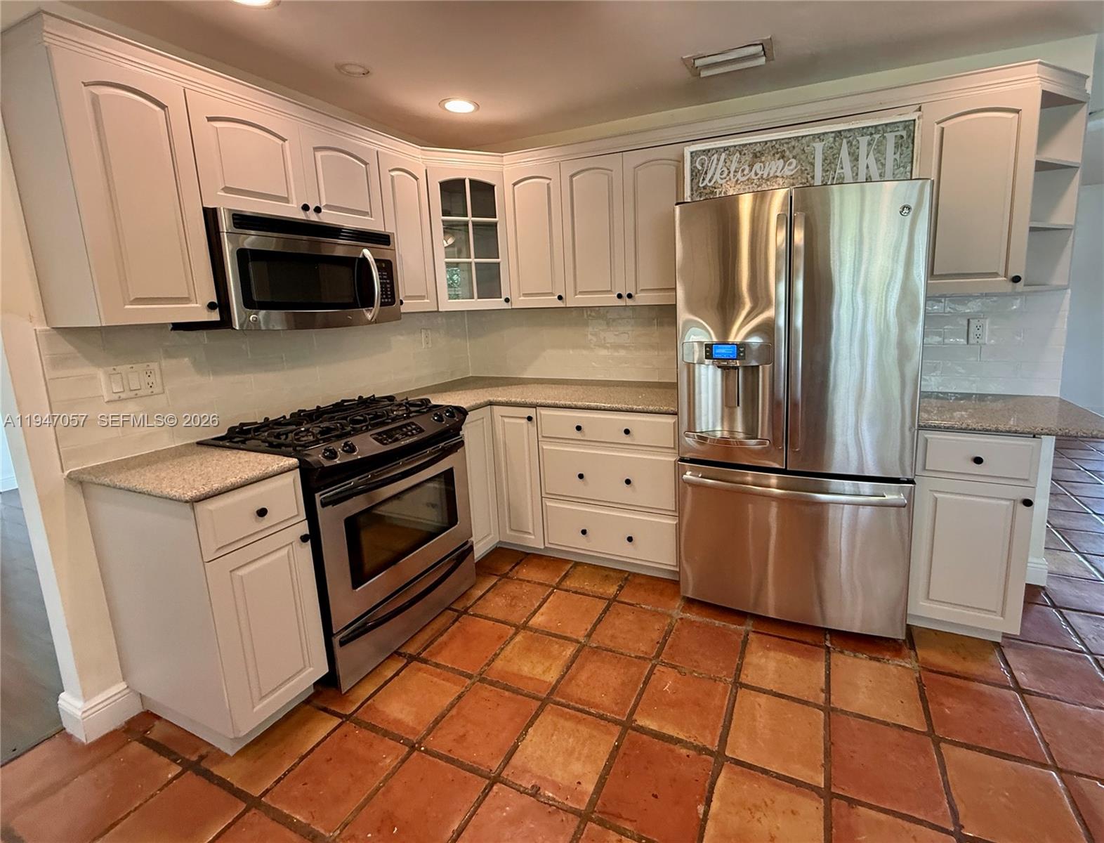 A kitchen features white cabinets, stainless steel appliances, granite countertops, and terracotta tile flooring — 12620 SW 114th Ave, Miami FL 33176, MIAMI, FL