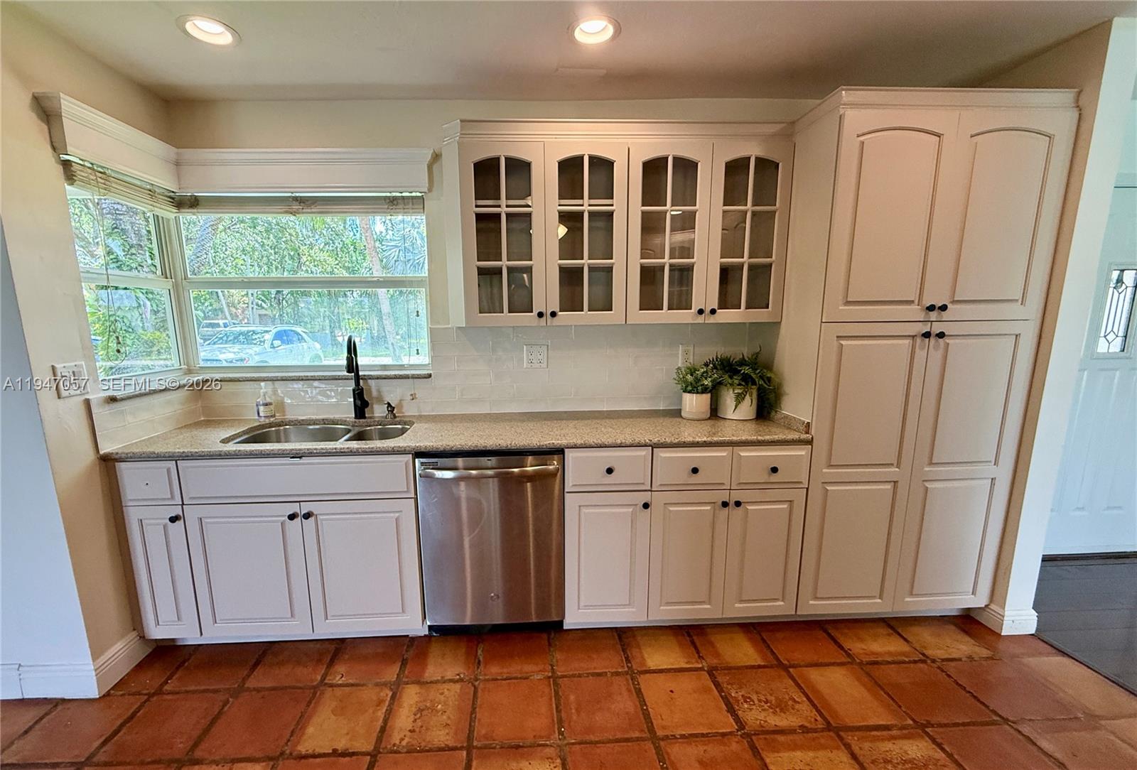 A kitchen features white cabinets, a stainless steel dishwasher, a sink, and terracotta tile flooring — 12620 SW 114th Ave, Miami FL 33176, MIAMI, FL