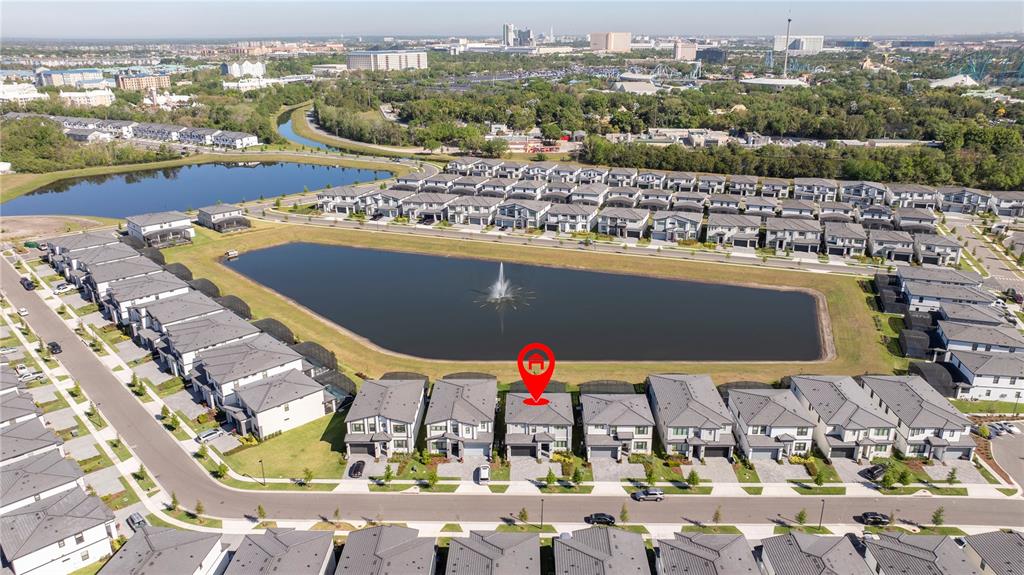 An aerial view shows a row of modern houses facing a lake with a fountain — 5860 HIGH SEAS DRIVE, ORLANDO, FL