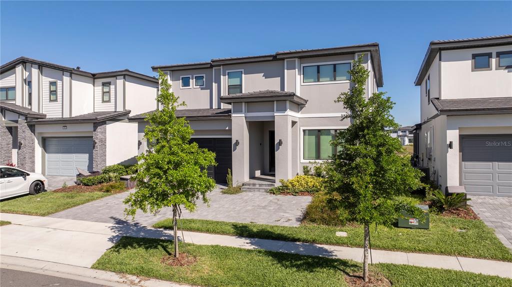 A two-story gray house with a paved driveway and two young trees in the front — 5860 HIGH SEAS DRIVE, ORLANDO, FL