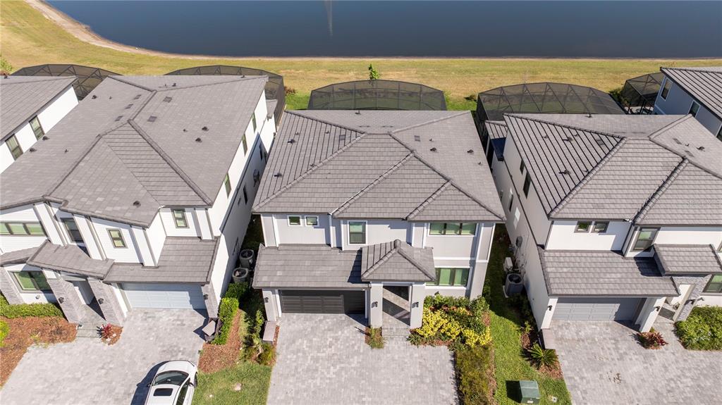 An aerial view shows three suburban houses with gray tile roofs and paved driveways — 5860 HIGH SEAS DRIVE, ORLANDO, FL