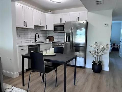 A kitchen features white cabinets, stainless steel appliances, a subway tile backsplash, and a dining table — 2500 HARN BLVD UNIT F22, CLEARWATER, FL