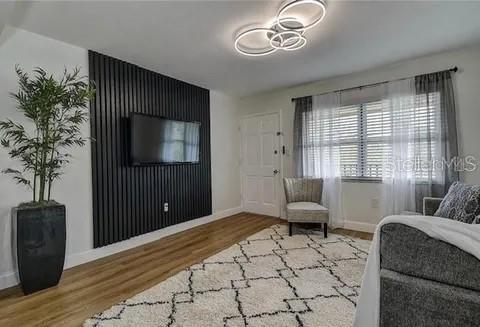 A living room features a black slatted accent wall with a mounted television and wood flooring — 2500 HARN BLVD UNIT F22, CLEARWATER, FL