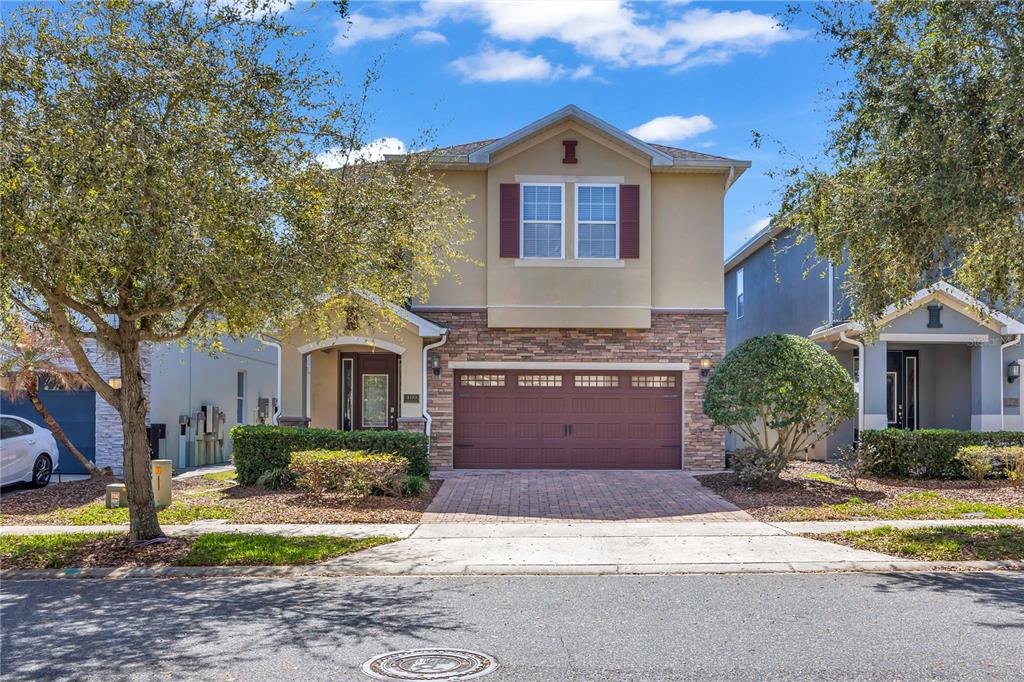 A two-story house with a stone facade, a two-car garage, and a paved driveway — 460 LASSO DRIVE, KISSIMMEE, FL