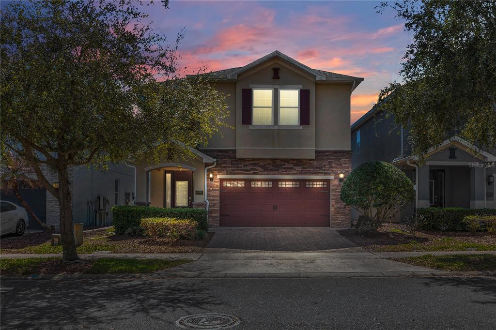 A two-story suburban house features a stone-accented facade, a double garage, and a paved driveway — 460 LASSO DRIVE, KISSIMMEE, FL