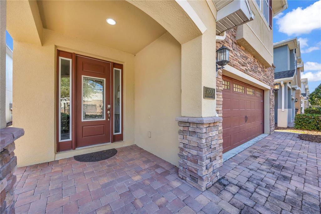 A paved entryway leads to a front door and a two-car garage with stone accents — 460 LASSO DRIVE, KISSIMMEE, FL