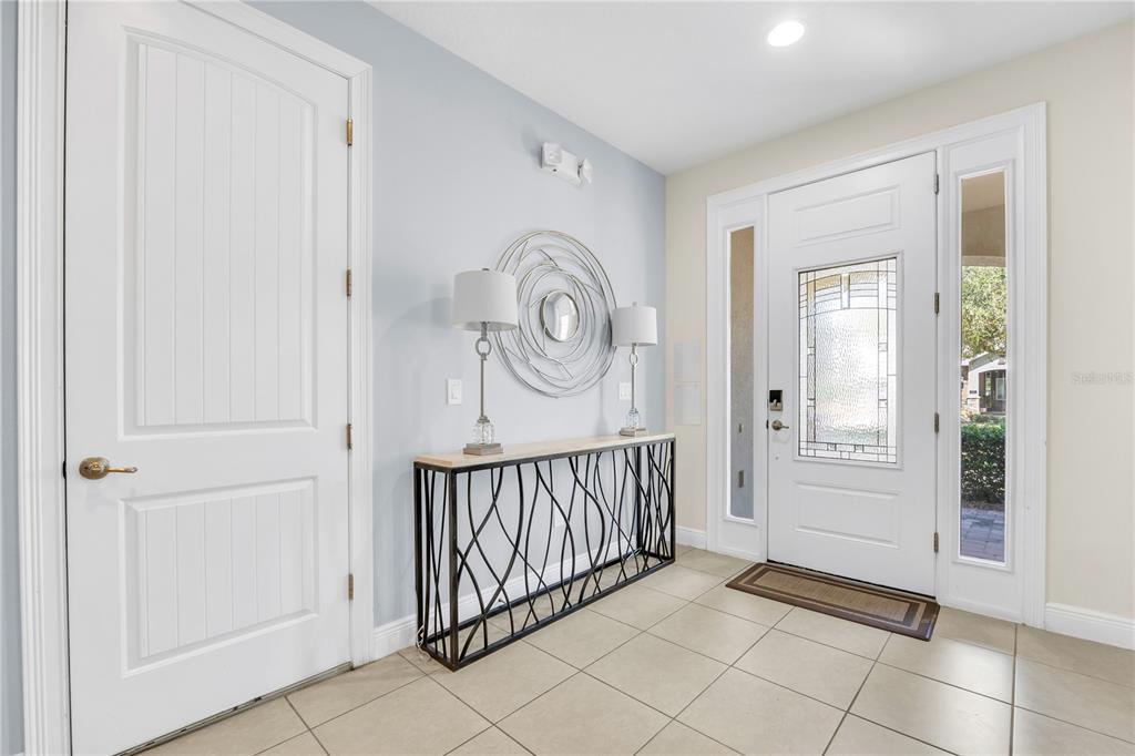 A bright entryway features a white front door, tile flooring, and a modern console table — 460 LASSO DRIVE, KISSIMMEE, FL