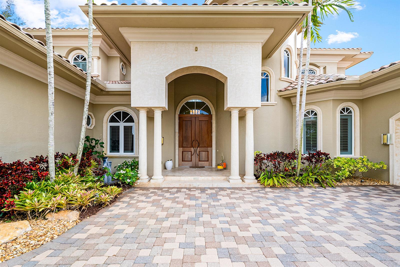 The exterior of a beige house features a paved driveway, arched windows, and double doors — 4304 Saint Andrews Drive, Boynton Beach FL 33436, BOYNTON BEACH, FL