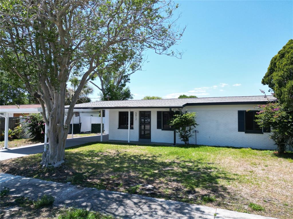 A single-story white brick house with a carport and a large tree in the yard — 5812 LIVERPOOL DRIVE, TAMPA, FL