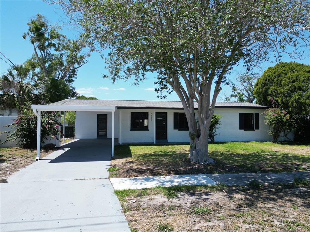 A single-story white brick house with a carport and a large tree in the yard — 5812 LIVERPOOL DRIVE, TAMPA, FL