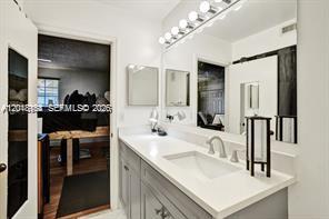 A bathroom features a gray vanity with a white countertop, a large mirror, and a doorway — 3901 San Simeon Ln, Weston FL 33331, WESTON, FL
