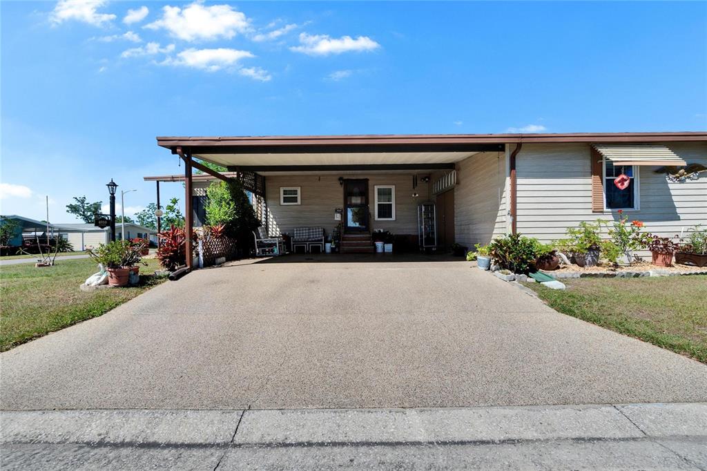 A single-story home with a large concrete driveway and an attached carport — 4910 LOCH NESS DRIVE, LAKELAND, FL
