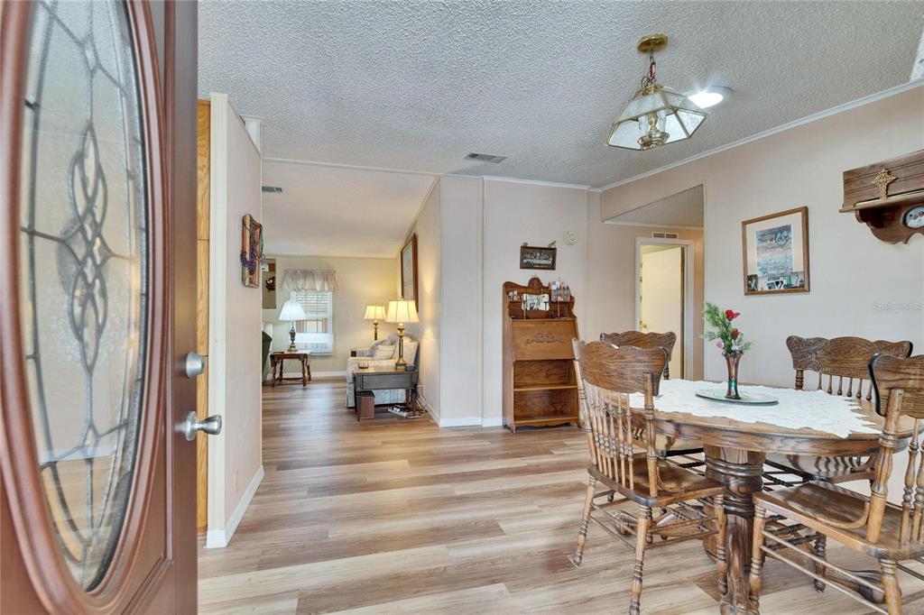 A dining area with a wooden table and chairs opens into a living room space — 4910 LOCH NESS DRIVE, LAKELAND, FL