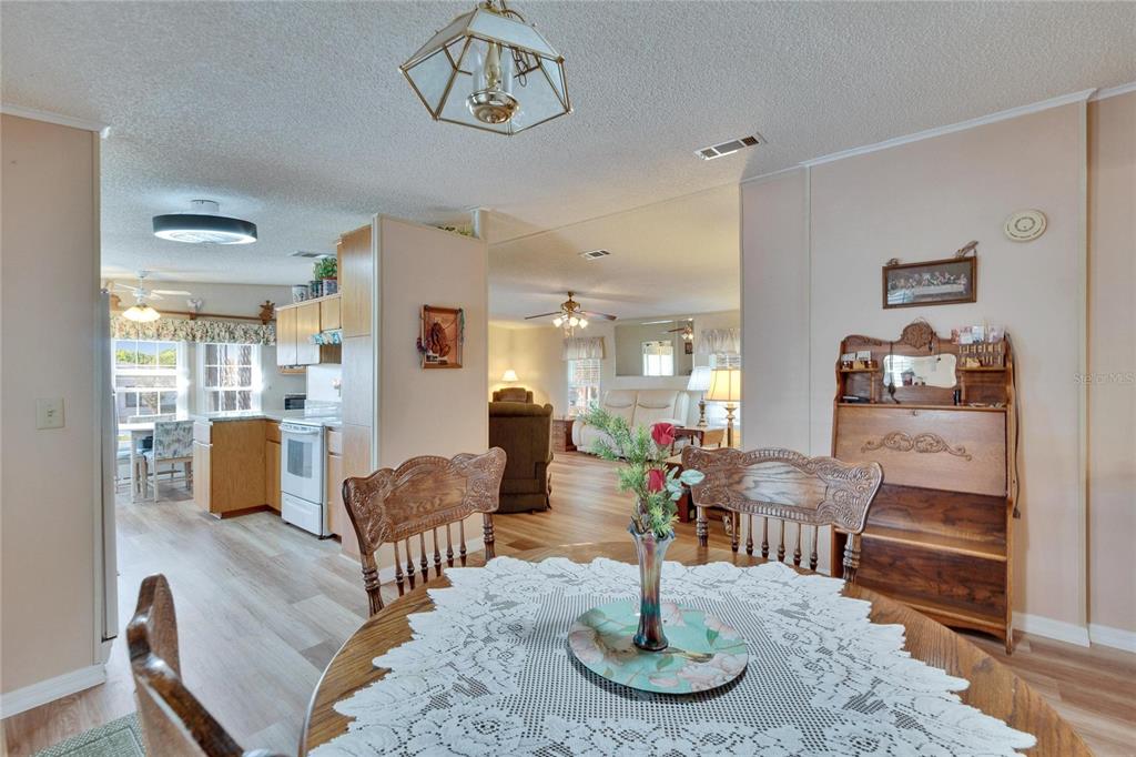A dining area with a round table leads into a kitchen and a living room — 4910 LOCH NESS DRIVE, LAKELAND, FL
