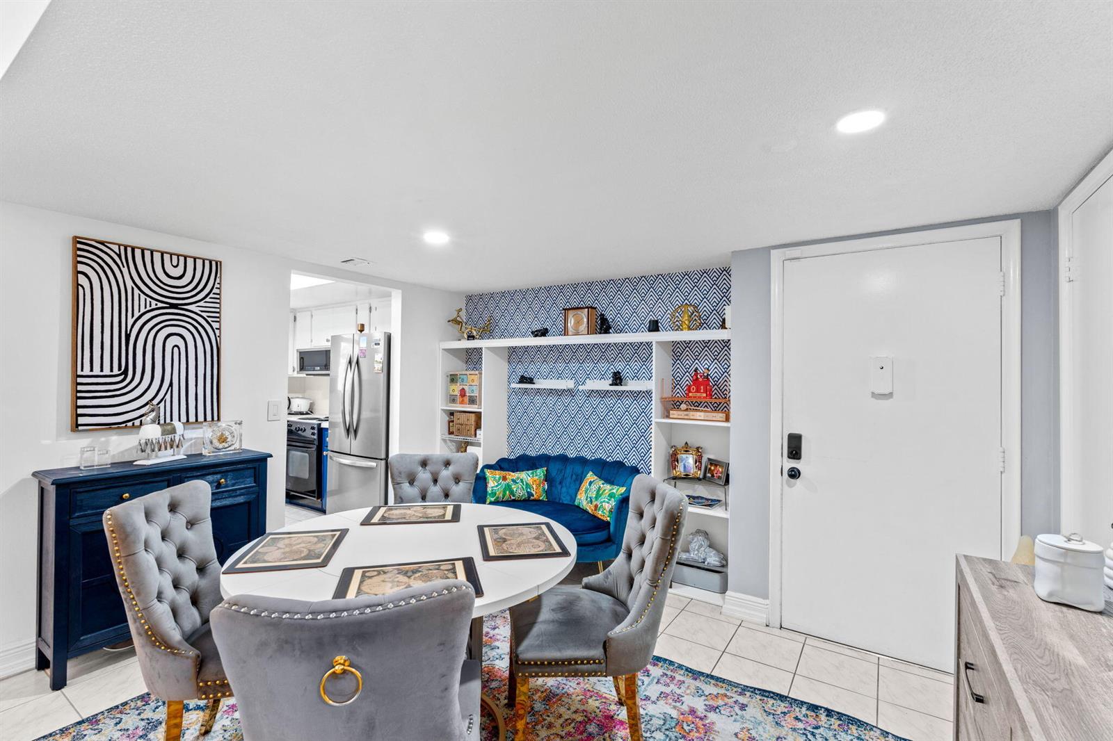 A dining area features a round table, tufted chairs, a blue sideboard, and patterned wallpaper — 2540 Boundbrook Boulevard # 209, Palm Springs FL 33406, PALM SPRINGS, FL