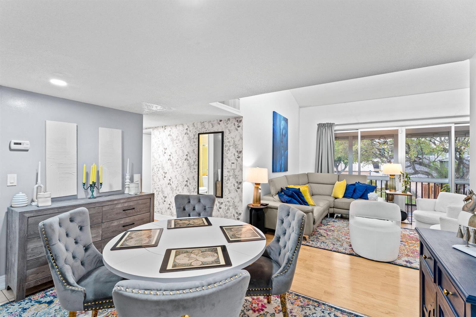 A dining area with a round table and tufted chairs opens into a living room — 2540 Boundbrook Boulevard # 209, Palm Springs FL 33406, PALM SPRINGS, FL