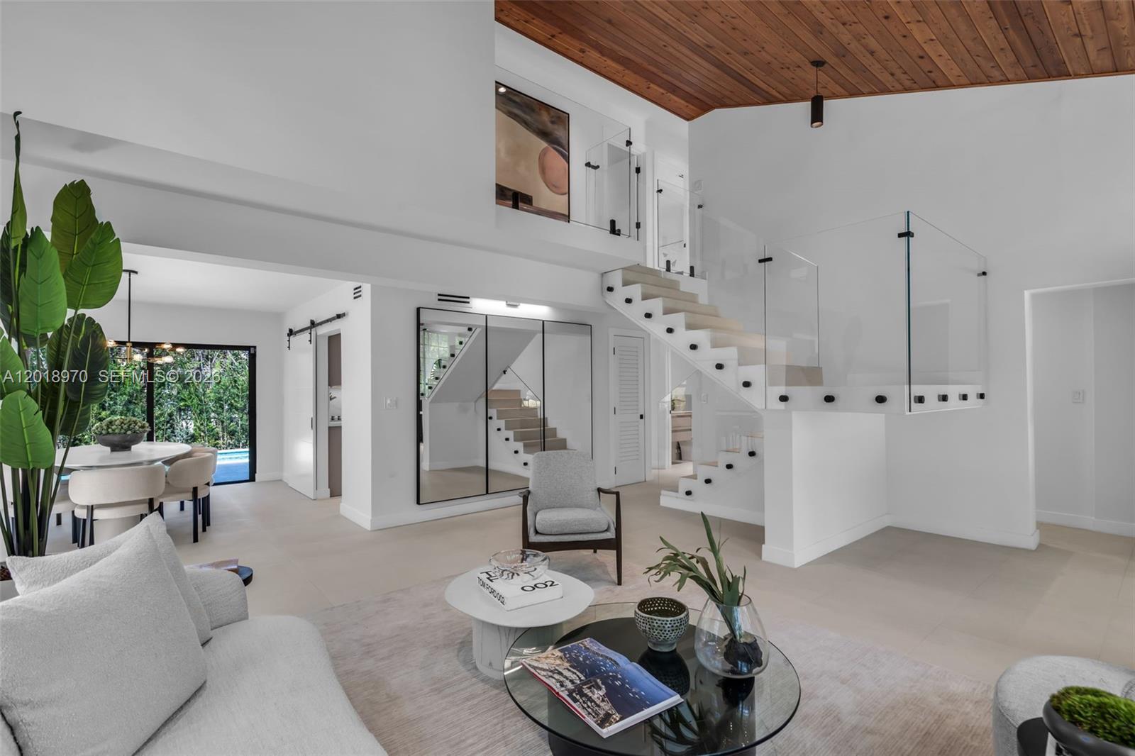 A modern living room features a floating staircase with glass railings and a wood-paneled ceiling — 1415 Trillo Ave, Coral Gables FL 33146, CORAL GABLES, FL