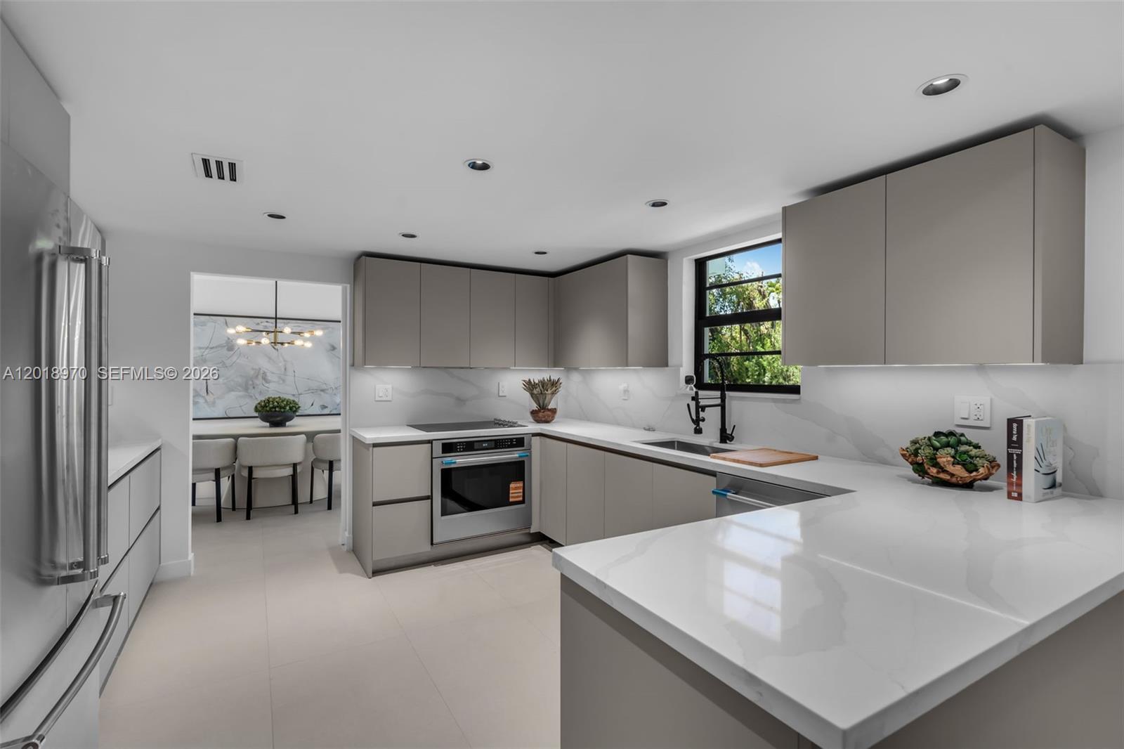A modern kitchen features grey flat-panel cabinets, white quartz countertops, and a marble backsplash — 1415 Trillo Ave, Coral Gables FL 33146, CORAL GABLES, FL