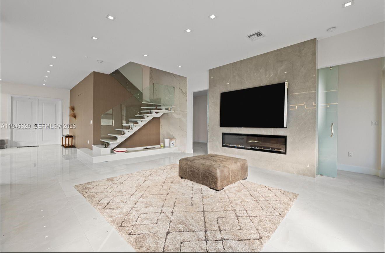 A modern living room features a floating staircase, a wall-mounted television, and a linear fireplace — 4499 SW 173rd Ave, Miramar FL 33029, MIRAMAR, FL