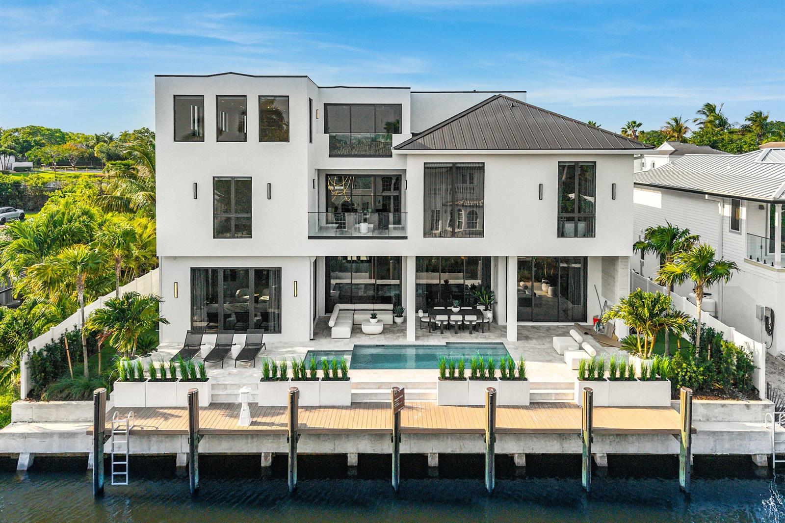 An aerial view of a modern three-story waterfront home with a pool and wooden dock — 748 NE 72nd Street, Boca Raton FL 33487, BOCA RATON, FL