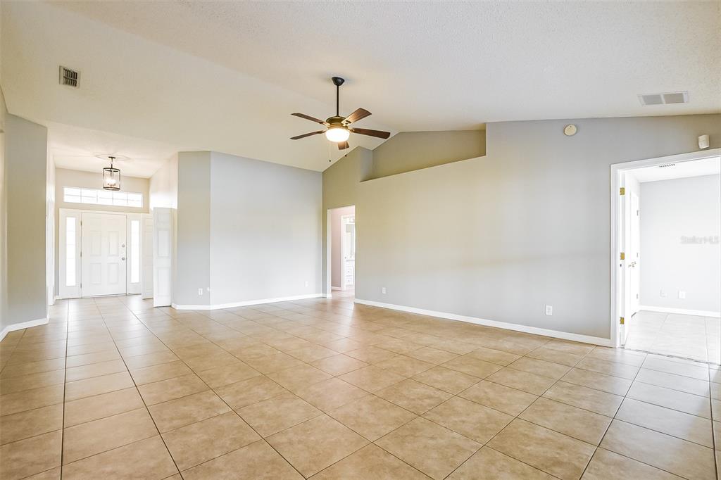 A spacious living room features light gray walls, tan tile flooring, and a ceiling fan — 2091 FAWN MEADOW CIRCLE, ST CLOUD, FL