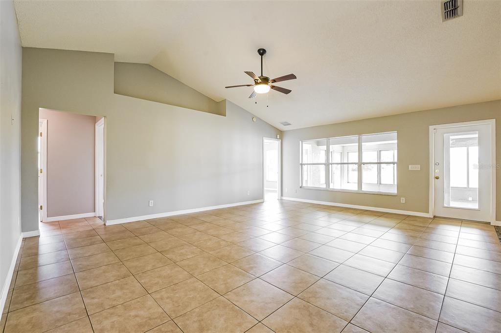 An empty living room with vaulted ceilings, tile flooring, and a ceiling fan — 2091 FAWN MEADOW CIRCLE, ST CLOUD, FL