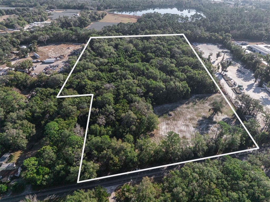 An aerial view shows a wooded lot outlined in white next to a cleared area — 589 S VOLUSIA AVENUE, PIERSON, FL