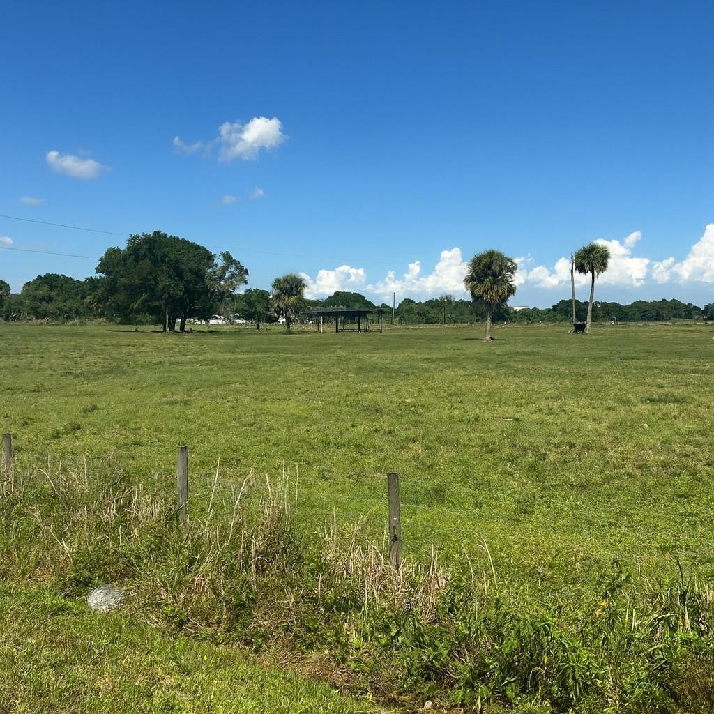A wide, grassy pasture features a small shelter, scattered trees, and a wire fence — 1202 NW 8th Avenue, Okeechobee FL 34972, OKEECHOBEE, FL