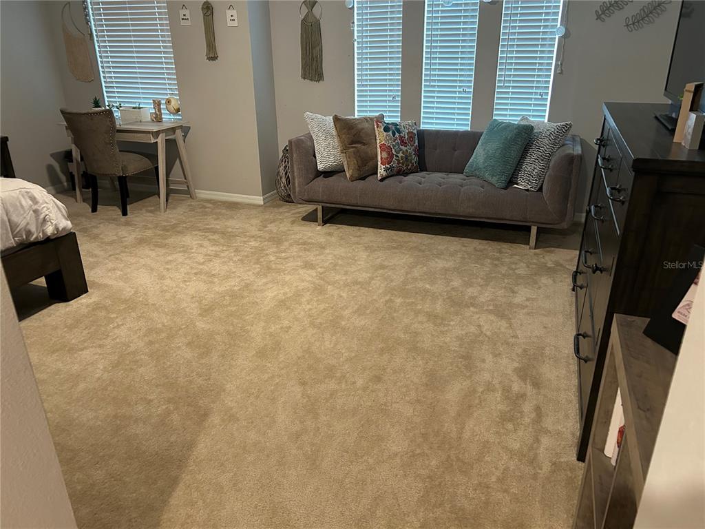 A bedroom features a gray sofa, a desk with a chair, and a dark wood dresser — 3363 BELLEZZA COURT, KISSIMMEE, FL