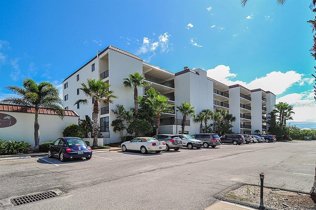 A multi-story apartment building with a parking lot in front under a blue sky — 6727 TURTLEMOUND ROAD UNIT 318, NEW SMYRNA BEACH, FL