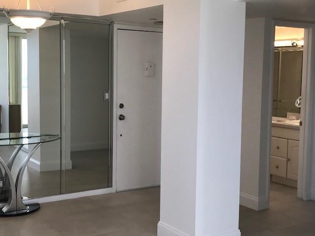 A white hallway features a mirrored closet, a glass-topped table, and an open bathroom doorway — 111 Briny Avenue # 14, Pompano Beach FL 33062, POMPANO BEACH, FL