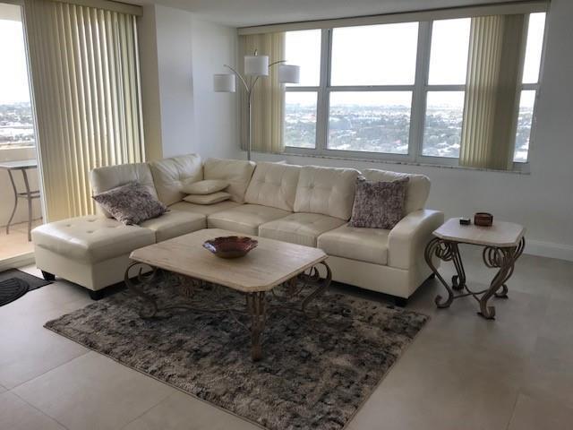 A living room features a white sectional sofa, a stone-top coffee table, and large windows — 111 Briny Avenue # 14, Pompano Beach FL 33062, POMPANO BEACH, FL