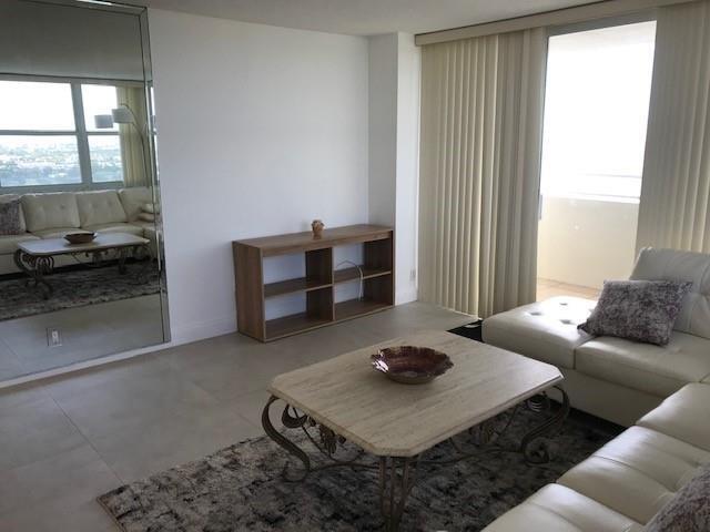 A living room features a white leather sofa, a stone coffee table, and a mirrored wall — 111 Briny Avenue # 14, Pompano Beach FL 33062, POMPANO BEACH, FL