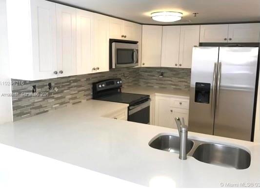 A kitchen features white cabinets, stainless steel appliances, a tiled backsplash, and a white countertop — 55 E 4th St # 102, Hialeah FL 33010, HIALEAH, FL