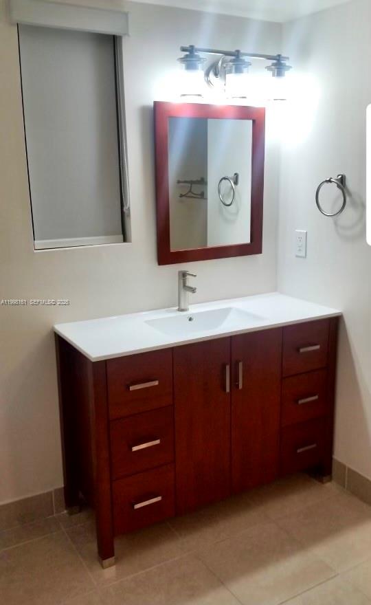 A bathroom features a wooden vanity with a white countertop, a mirror, and overhead lighting — 55 E 4th St # 102, Hialeah FL 33010, HIALEAH, FL