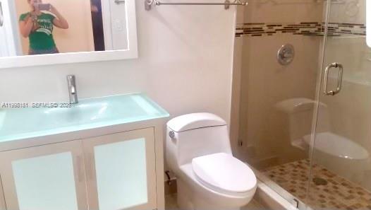 A bathroom features a glass-topped vanity, a white toilet, and a glass-enclosed walk-in shower — 55 E 4th St # 102, Hialeah FL 33010, HIALEAH, FL