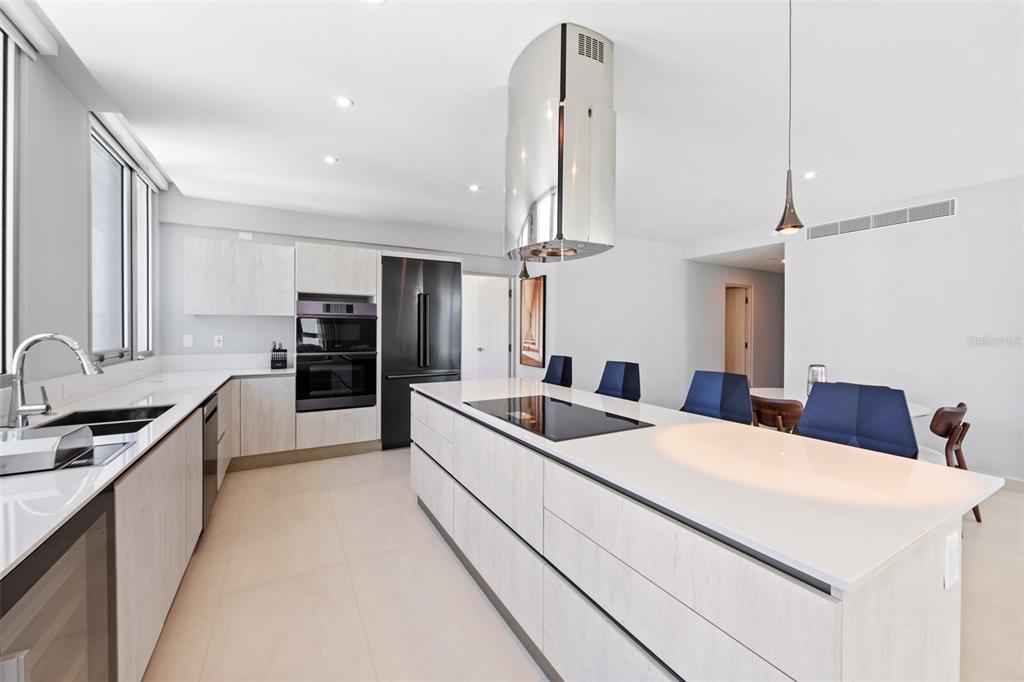 A modern kitchen features a large white island, stainless steel appliances, and light wood cabinetry — 14 CALLE DELCASSE UNIT 703, SAN JUAN, PR
