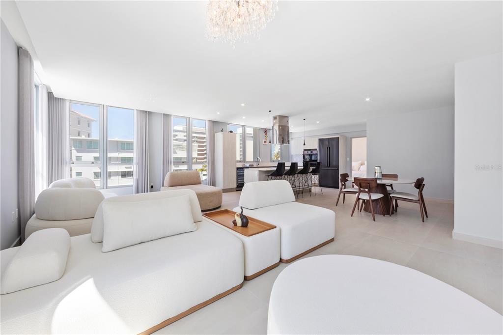 A bright, open-concept living and dining area features white modern furniture and a kitchen island — 14 CALLE DELCASSE UNIT 703, SAN JUAN, PR