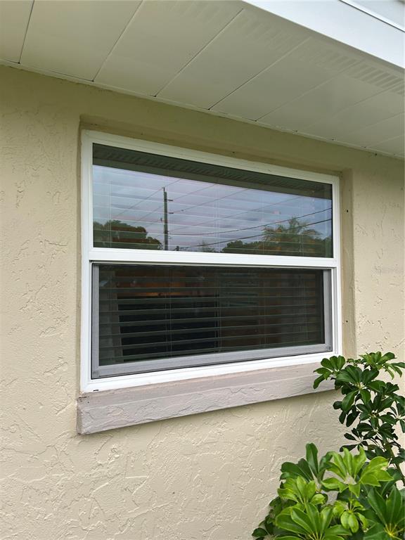 A single-hung window with a screen is set into a beige stucco exterior wall — 209 MATISSE CIRCLE, NOKOMIS, FL